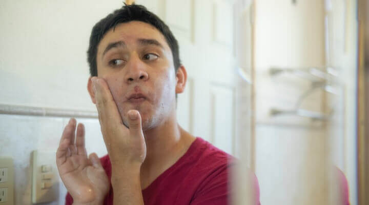 Young man applying facial cream