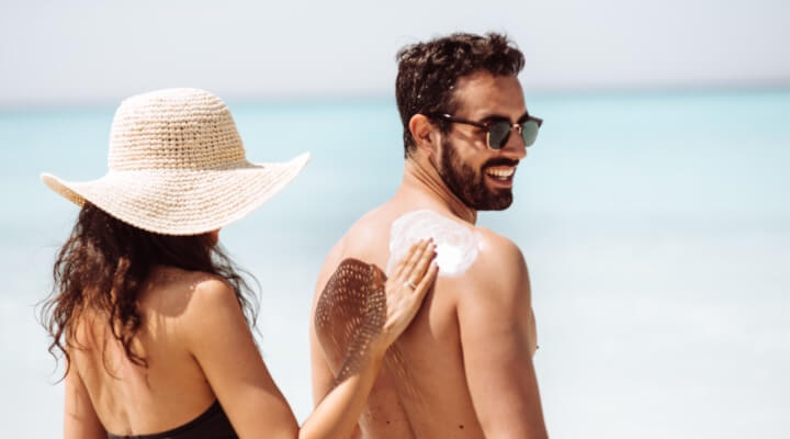 woman applying sunscreen to man's back