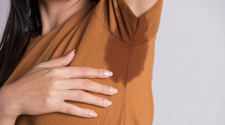 Woman inspects her armpits for sweat.