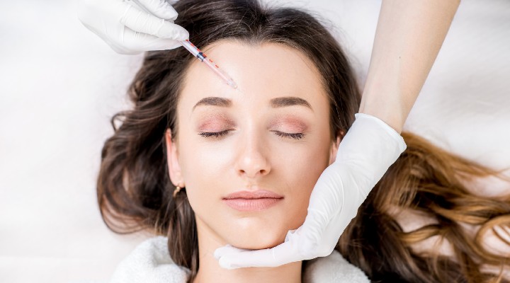 Woman receives a botox injection in her forehead.