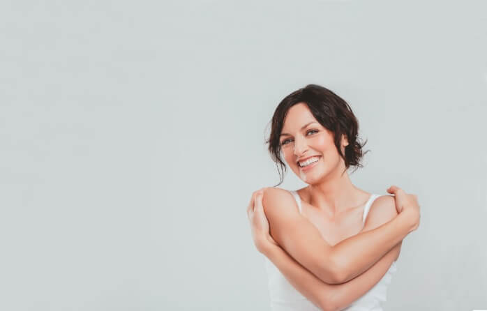 woman smiling and hugging herself