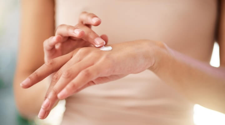 woman putting lotion on hand