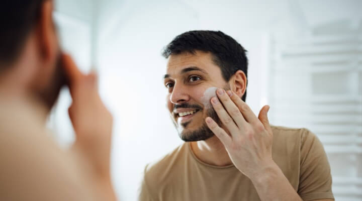 man putting lotion on face